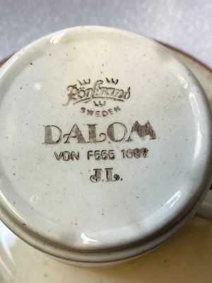 Dalom Kaffeservis - Klassisk Dalom-kaffeservis från Rörstrand, Sweden. Setet inkluderar koppar och fat med vackra bruna och blå ränder. Märkt VDN F555 1082, J.L. Servisen är i fint vintage-skick med minimalt slitage, perfekt för samlare eller vardagsbruk.