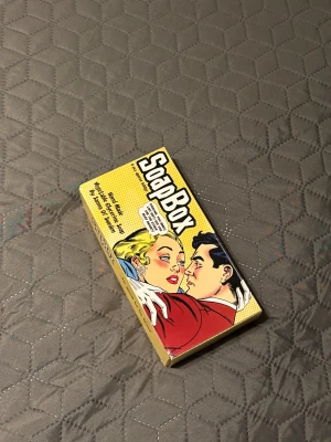 SoapBox presentförpackning med tvål - Aldrig använd!! SoapBox presentförpackning med sex handgjorda tvålar i olika färger och dofter som kokos, lavendel, hallon och choklad. Tvålarna är formade som tårtbitar och har en cool retroförpackning med pop art-design. Perfekt som present eller för att testa olika dofter.