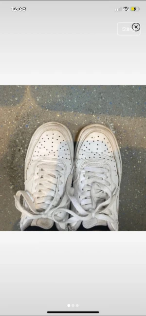 Vita Nike sneakers - Fräscha vita Nike sneakers med klassisk låg siluett. Skorna har perforerad tå, snörning och platt sula. Tillverkade i skinn med diskret Nike-logga på hälen. Perfekta för dig som gillar clean och tidlös streetstil.