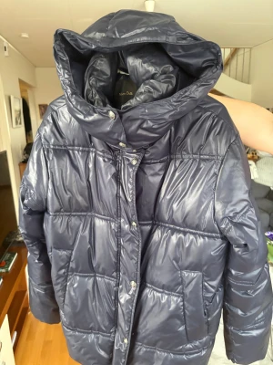 Mörkblå pufferjacka från Massimo Dutti - Säljer en mörkblå pufferjacka från Massimo Dutti med stor huva och snygga silverfärgade knappar. Jackan har en quiltad look, två stora fickor framtill.