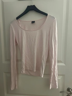 Ljusrosa långärmad topp från Gina Tricot - Säljer en enkel och mjuk ljusrosa långärmad topp från Gina Tricot. Toppen har rund halsringning och är tillverkad i tunn bomull som känns skön mot huden. 
