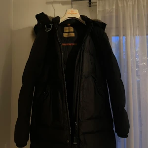 Svart dunjacka med päls från Parajumpers - Säljer en svart dunjacka från Parajumpers med stor huva och lyxig pälsdetalj. Jackan har dragkedja framtill och är perfekt för kalla dagar. Klassisk pufferstil och riktigt varm. Äkta. Pris kan diskuteras