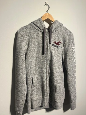 Hollister Zip Hoodie - Hej! Säljer nu denna väldigt snygga Hollister Zip Hoodien.  Storlek S Small   Färg: Grå & Vit Skick: Mycket gott – endast använd vid enstaka tillfällen  Skickas spårbart eller hämtas upp efter överenskommelse. Vid intresse – hör gärna av dig.  Skriv vid frågor eller ifall du vill ha fler bilder:) 