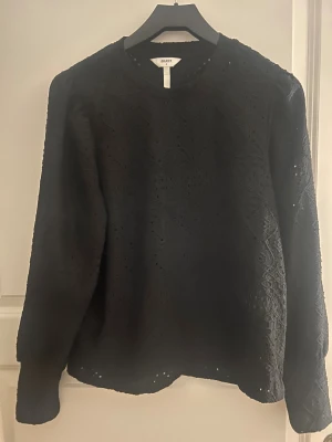 Svart spetsmönstrad tröja från Object - Svart långärmad tröja från Object med snyggt spetsmönster över hela plagget. Rund halsringning och mjukt material som känns skönt mot huden. Perfekt för dig som gillar detaljer och vill ha en unik look.