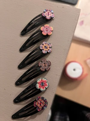 6-pack blommiga hårspännen -  ✨ Handgjord håraccessoar ✨ 6 st för 150 kr, om man vill ha en kostar dom 25 kr st❤️  Unik, kreativ och hållbar – den här håraccessoaren är tillverkad för hand av second hand-knappar som fått nytt liv i en modern och lekfull design.   Varje knapp bär på en egen historia och tillsammans skapar de ett personligt uttryck som gör din frisyr speciell.  Finns diadem, hårspännen och små-klipp✨  Intresserad av mer?  Få 25% rabbatt på en bundle!🛍️  Perfekt för dig som vill: * Addera en färgstark detalj til