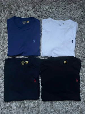 4st Polo Ralph Lauren t-shirts - Fyra klassiska t-shirts från Polo Ralph Lauren i färgerna navy, blå, vit och svart. Alla har rund halsringning och den ikoniska broderade loggan på bröstet. Tillverkade i mjuk bomull för en skön känsla och perfekt passform. Navy svart och den vita tröjan är i classic fit medans den blåa är i slim fit.