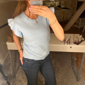 Stickad t-shirt - En jättefin blå, stickad och varm t-shirt med volang. I storlek xs/s från Vila. Använd en gång. Köpte för 350kr💗