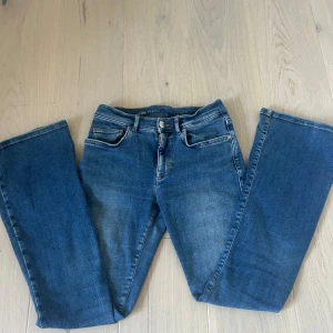 Blå bootcut jeans från Vero Moda  - Snygga blå bootcut jeans från Vero Moda med klassisk femficksdesign och medel midja. Jeansen har en lätt tvättad look och är tillverkade i mjukt denimtyg. Perfekta för dig som gillar en avslappnad men trendig stil. Säljer då dem bärjar bli för små. Kontakta vid frågor om specifika mått