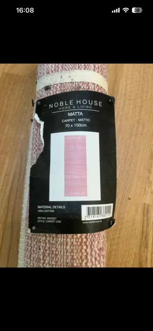 Noble House Matta 70x150cm - Snygg matta från Noble House, modell Carpet Ove, i storlek 70x150 cm. Tillverkad i 100% bomull och levereras rullad i originalförpackning. Färgen är rosa/vit. mattan är oanvänd .