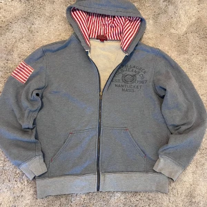 Zip hoodie från Ralph Lauren Polo Jeans - Riktigt fet ljusblå/grå zip hoodie från Ralph Lauren Polo Jeans company med väldigt snygga detaljer!  Står storlek L men passar mer S/M.