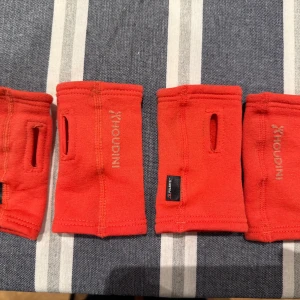 Röda fleecehandledsvärmare för barn Houdini, 2 par - Säljer två par röda handledsvärmare från Houdini i mjuk fleece. De har tumhål och är perfekta för att hålla händerna varma utan att täcka hela handen. Snygg minimalistisk design med diskret Houdini-logga på sidan. Strl 5/7. Har används av våra tvillingkillar. 