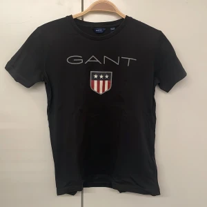 Svart GANT t-shirt - En gant T-shirt i  bra skick som är lite solblekt på ryggen som knappt syns. Annars super bra skick och super skön tröja. Tveka inte på att höra av er vid frågor😊