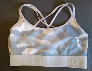 Camo sport-bh från Better Bodies - Sport-bh från Better Bodies i ljusgrått och vitt camouflagemönster. Snygga korsade axelband i ryggen och bred resår med logga. Perfekt för träning och gym. Tillverkad i mjukt och stretchigt syntetmaterial för bästa komfort.