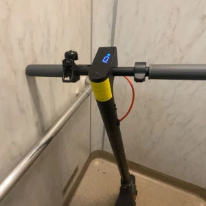 Elsparkcykel med digital display - Modern elsparkcykel med digital display, ringklocka och bekvämt styre. Svart design med gula och röda detaljer. Ser ut att vara i gott skick utan synligt slitage. Perfekt för smidig och miljövänlig transport i stadsmiljö.