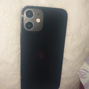 iPhone 12 mini - Snygg svart iPhone 12 mini med dubbla kameror och klassisk design. Telefonen visar tecken på slitage runt kanterna men fungerar och startar som den ska. Perfekt för dig som vill ha en kraftfull och pålitlig smartphone till ett bra pris.