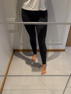 Mörkgrå skinny jeans med hög midja - Säljer ett par svarta skinny jeans med hög midja och klassisk femficksdesign. Jeansen har smal passform hela vägen ner och är tillverkade i stretchigt denim för extra komfort.