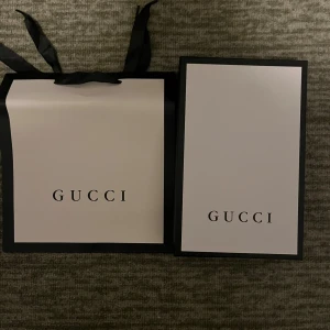 Svart Gucci bälte med GG-spänne - Säljer ett svart Gucci bälte i skinn med klassiskt GG-spänne i både silver och guld. Bältet har diskret GG-mönster längs remmen och levereras med originalbox, dustbag och certifikat. Perfekt accessoar för att lyfta din outfit med lyxig känsla.