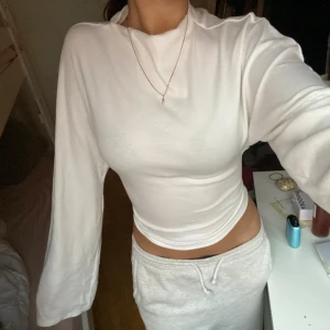 Vit croppad långärmad tröja - Säljer en vit croppad långärmad tröja med rund hals och loose passform i ärmarna. Tröjan är enkel och stilren, perfekt att matcha med jeans eller mjukisbyxor. Materialet känns mjukt och skönt mot huden, troligen bomull eller polyester.