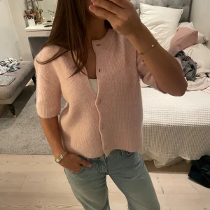Ljusrosa kofta från Gina Tricot - Superfin ljusrosa kofta från Gina Tricot med korta ärmar och rund hals. Koftan är ribbstickad och har knappar framtill. Den är använd en gång och är inte nopprig! Kontakta om du har fler frågor 💓