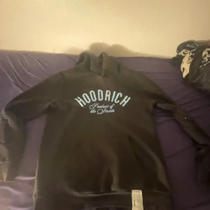 Svart hoodie från Hoodrich med tryck - Svart hoodie från Hoodrich med stort tryck på bröstet och ryggen. Tröjan har huva, lång ärm och en diskret dragkedja på ena ärmen. Materialet är mjukt och känns som bomull eller polyester. Perfekt för dig som gillar streetwear och snygga detaljer. Lite solbränd därför säljs det så billigt. Jätte sällsynt tröja. Storlek M men passar även L