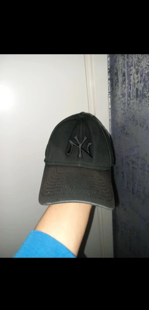 Svart New Era NY Yankees keps - Snygg svart keps från New Era med NY Yankees-logga broderad framtill. Modellen är 9FORTY och har böjd skärm samt justerbar passform. Tillverkad i 100% bomull för skön känsla. Perfekt för dig som gillar sportig streetstyle och klassiska baseball-vibes.