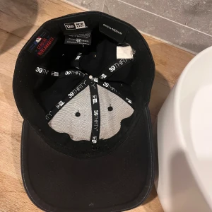 Svart New Era Yankees keps - Snygg svart New Era 39THIRTY keps med broderad New York Yankees-logga framtill och diskret New Era-märke på sidan. Flexfit-modell med böjd skärm, tillverkad i bomull. Perfekt för dig som gillar sportig streetstyle.