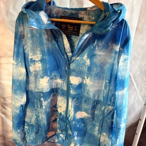 Blå mönstrad vindjacka Woolrich - Sjukt snygg och ovanlig jacka från Woolrich i storlek L/XL men sitter som en M. Tags följer med jackan är i ny skick!🤩