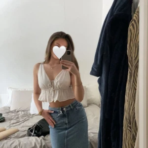 Vit linnetopp med snörning - Vit linnetopp med snörning framtill och volangkant nedtill, ärmlös med djup v-ringning och croppad passform, från BikBok!