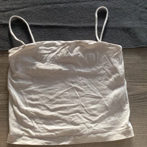 Vit linnetopp från Gina Tricot - Säljer en enkel och fräsch vit linnetopp från Gina Tricot i storlek S. Toppen har smala axelband och är tillverkad i mjuk bomull, perfekt för varma dagar. Stilren och lätt att matcha med jeans eller kjol.
