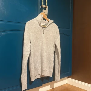 Ljusgrå half zip tröja Selected Homme - Säljer en ljusgrå stickad tröja från Selected Homme i storlek S. Tröjan har en ribbad krage med half zip-dragkedja och långa ärmar. Perfekt för lager-på-lager och enkel att matcha med det mesta.