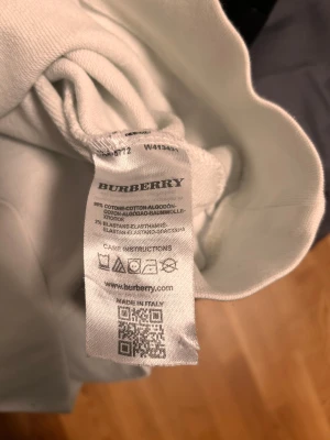 Vit sweatshirt från Burberry, M - Vit sweatshirt från Burberry med svart tryck framtill och klassisk rund hals. Tröjan är i mjuk bomullsmix med lite stretch för extra komfort. Långärmad och stilren design som lyfter din outfit med en lyxig touch.