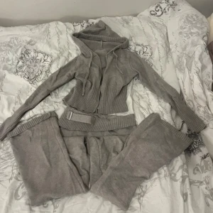 Grå stickad mjukisset - Jätte fint mjukisset! Byxorna är lågmidjade och i bootcut, zip tröjan är i kort modell och figur sydd. Varm till vintern. Materialet går att stretcha ut, skulle säga de passar s och m