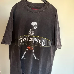 Svart Godspeed t-shirt med skelettprint - Cool svart t-shirt från Godspeed med stort skelettmotiv och text på framsidan samt stor vit grafisk print på ryggen. Oversized fit och tillverkad i mjuk bomull. Perfekt statement-plagg för dig som gillar streetwear och unika prints.