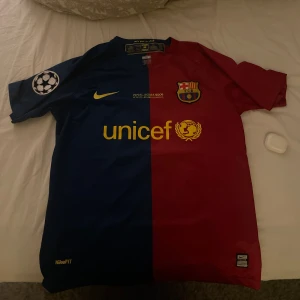 Barcelona Messi 10 fotbollströja Nike - Säljer en ikonisk FC Barcelona fotbollströja från Nike med Messi 10 på ryggen. Tröjan har klassisk halva röd och halva blå design, korta ärmar och gula detaljer som Unicef-logga och Nike-swoosh. Materialet är lätt och andas, perfekt för match eller träning.