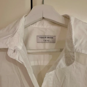 Vit skjorta från Tiger of Sweden - Klassisk vit skjorta från Tiger of Sweden med snygg krage och knappar framtill. Skjortan har lång ärm och är tillverkad i mjuk bomull. 