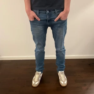 Replay Anbass jeans  - Snygga Replay Anbass jeans i en ljusblå tvätt med diskreta slitningar och klassiska fem fickor. Modellen har smal passform och raka ben, med coola detaljer på bakfickorna. Perfekt för dig som gillar stilrena och moderna jeans.