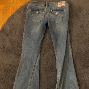 True Religion Joey ljusblå flare jeans - Säljer ett par ljusblå Joey jeans från True Religion med låg midja och flare-ben eftersom de tyvärr är köpta i fel storlek. Använda 4-5 gånger , ytterst lite slitna i kanten men för priset är de en bra deal!! Kan skicka bild på det om ni skriver privat🥰