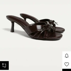 Bruna klackar  - Snygga mörkbruna sandaler med låg klack och öppen tå. Skorna har tunna remmar och en söt rosettdetalj framtill. Tillverkade i glansigt skinnmaterial som ger en elegant look. Perfekta för dig som gillar stilrena och trendiga skor.