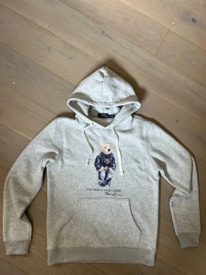 Ralph Lauren polo bear hoodie - Skick: 8/10 (väldigt bra skick) Färg: Grå Storlek: M (mått kan skickas privat) Defekter: Nej Märke: Ralph Lauren (polo bear) Vid frågor är det bara att höra av sig:) Fraktar inom 24h🚚📦