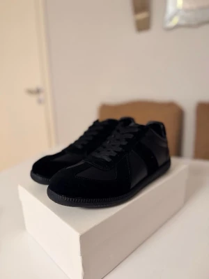 Svarta gats sneakers  - Gats sneakers i helsvart med snygga paneler i mocka och skinn. Klassisk rund tå, platt sula och snörning framtill. Stilren och minimalistisk design som passar till många olika outfits. Kommer med originalkartong.
