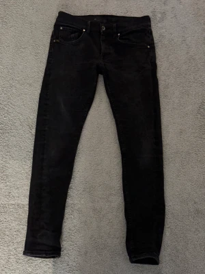 Tiger of Sweden jeans - ✅31/30 - SLIMFIT MODELL✅.Svarta tiger of Sweden slim fit modell  jeans med slim passform och klassisk femficksdesign. Jeansen har en mörk tvätt, silverfärgade nitar och knapp, samt Levi's-logga på myntfickan. Materialet är jeans med stretch för extra komfort. Perfekt för dig som gillar en smal siluett. 