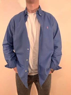 Blå Ralph Lauren skjorta - En stilren skjorta från  Ralph Lauren. Second hand men i väldigt fint skick ✨ Tvättad och struken – redo att användas direkt.  Perfekt för alla årstider, funkar både uppklätt och casual. Inga defekter och loose fit.  Storlek 👔: L  (något längre och vidare i modellen) Nypris 💰: ca 1 300 kr 