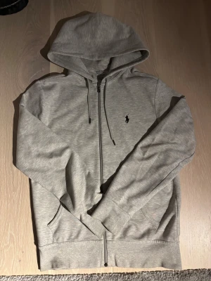 Grå Raulph Lauren hoodie med zip  - Säljer en Raulph Lauren zip i XS. Den är i bra skick och har inga defekter. Ordinarie pis 2300. Vid frågor eller intresse är det bara att höra av sig. Pris går att diskutera. 