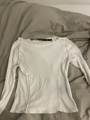 Vit ribbad långärmad topp XS - Säljer en vit långärmad topp från 157 Collection i storlek XS. Toppen är ribbad med råa kanter och har en figurnära passform. Perfekt att styla med jeans eller kjol för en clean look.