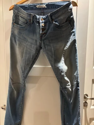 Blå skinny jeans från Fishbone Sister W29 - Säljer ett par blå skinny jeans från Fishbone Sister i storlek W29. Jeansen har klassisk femficksdesign, knappgylf och snygga slitningar på låren. Materialet är jeans med en ljus tvätt och smal passform som sitter tajt längs benen.