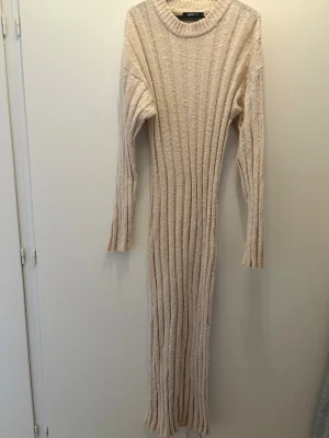 Beige stickad långklänning Gina Tricot - Säljer en beige stickad långklänning från Gina Tricot i storlek M. Klänningen har ribbad struktur, långärmade ärmar och rund halsringning. Perfekt för dig som gillar mjuka material och enkel, stilren design.