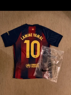 Ingen sko syns på bilderna - Bilderna visar en FC Barcelona fotbollströja med Lamine Yamal och nummer 10 på ryggen, samt detaljer som klubbmärke och sponsorlogga. Ingen sko eller skorelaterad produkt finns med på bilderna.