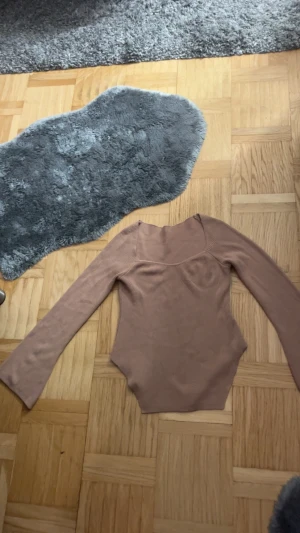Beige ribbad långärmad topp från SHEIN - Säljer en beige ribbad långärmad topp från SHEIN i storlek S. Toppen har en snygg v-ringad hals och figurnära passform med markerad midja. Materialet är mjukt och stretchigt, perfekt för att styla med jeans eller kjol.