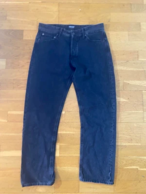 Svarta relaxed jeans från Jack & Jones - Säljer ett par svarta jeans från Jack & Jones, modell Relaxed/Chris. De har en loose passform med raka ben och klassisk femficksdesign. Jeansen är tillverkade i slitstarkt denim och har knappgylf. Perfekta för dig som gillar avslappnad stil.