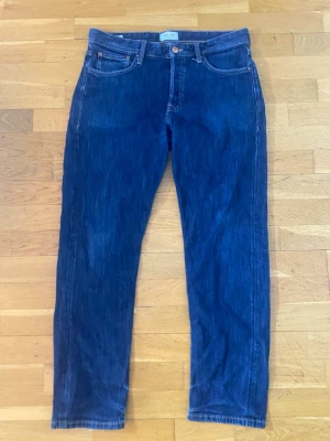 Blå loose fit jeans från Jack & Jones - Säljer ett par blå jeans från Jack & Jones, modell Loose/Chris. De har klassisk femficksdesign, raka ben och loose fit för en chill look. Materialet är slitstarkt jeans och färgen är mörkblå. Perfekta om du gillar avslappnad stil och vill ha bekväma jeans.